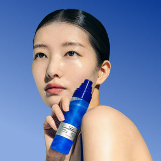 Model holding 1% Blue Peptide Cica Skin Booster bottle against a blue sky